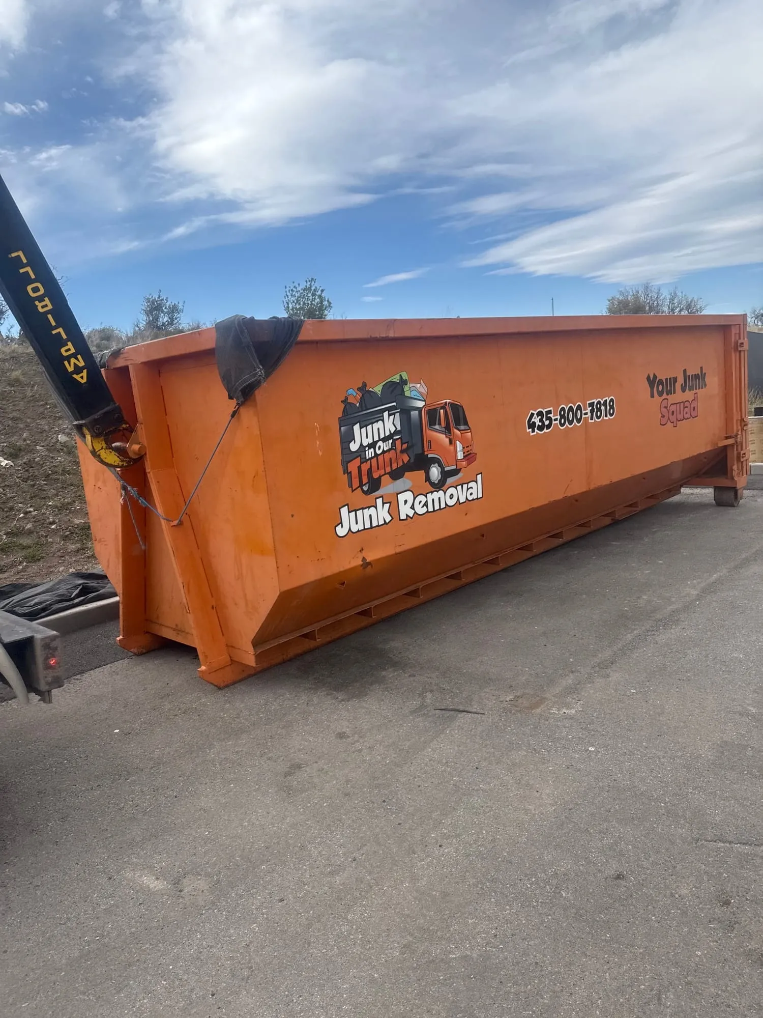 Junk In Our Trunk truck setting down an orange roll-off dumpster