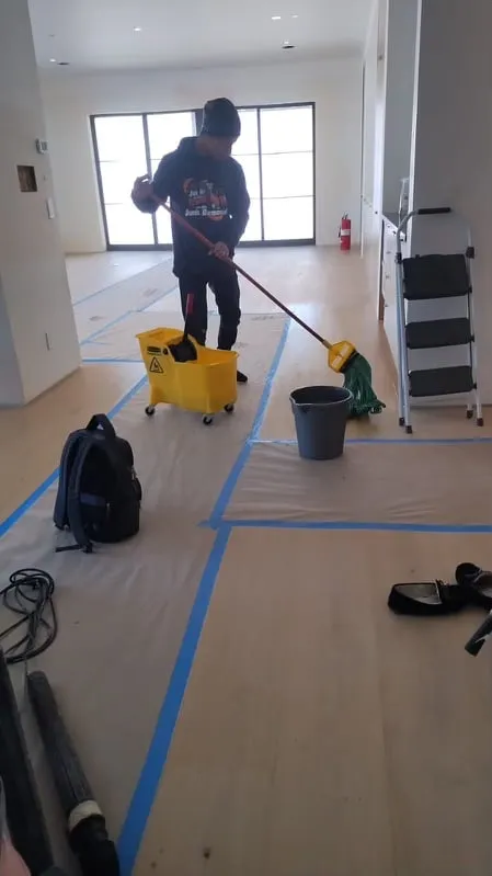 Cleaner mopping a new floor protected with blue tape