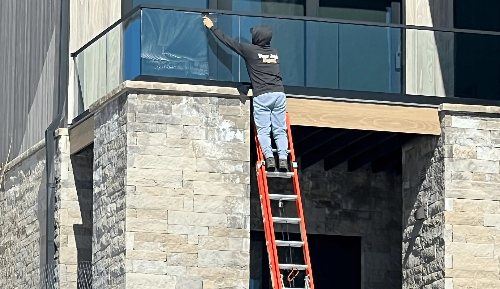 Window cleaner on a ladder at a stone-clad building