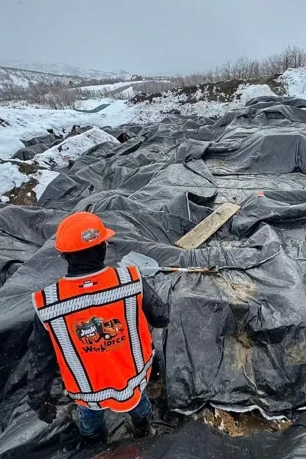 Workforce crew member in a hi-vis vest laying snow blankets
